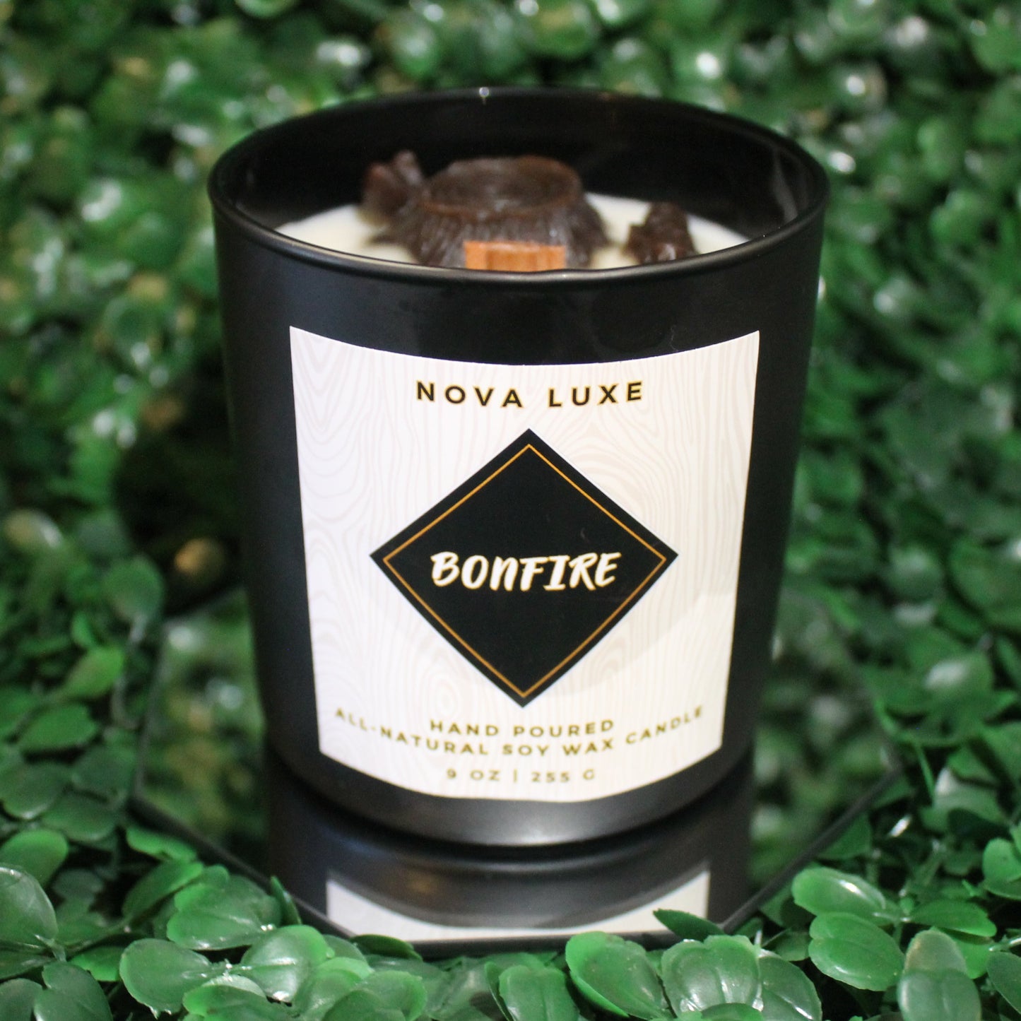 Nova Luxe Bonfire candle on a green leafy background