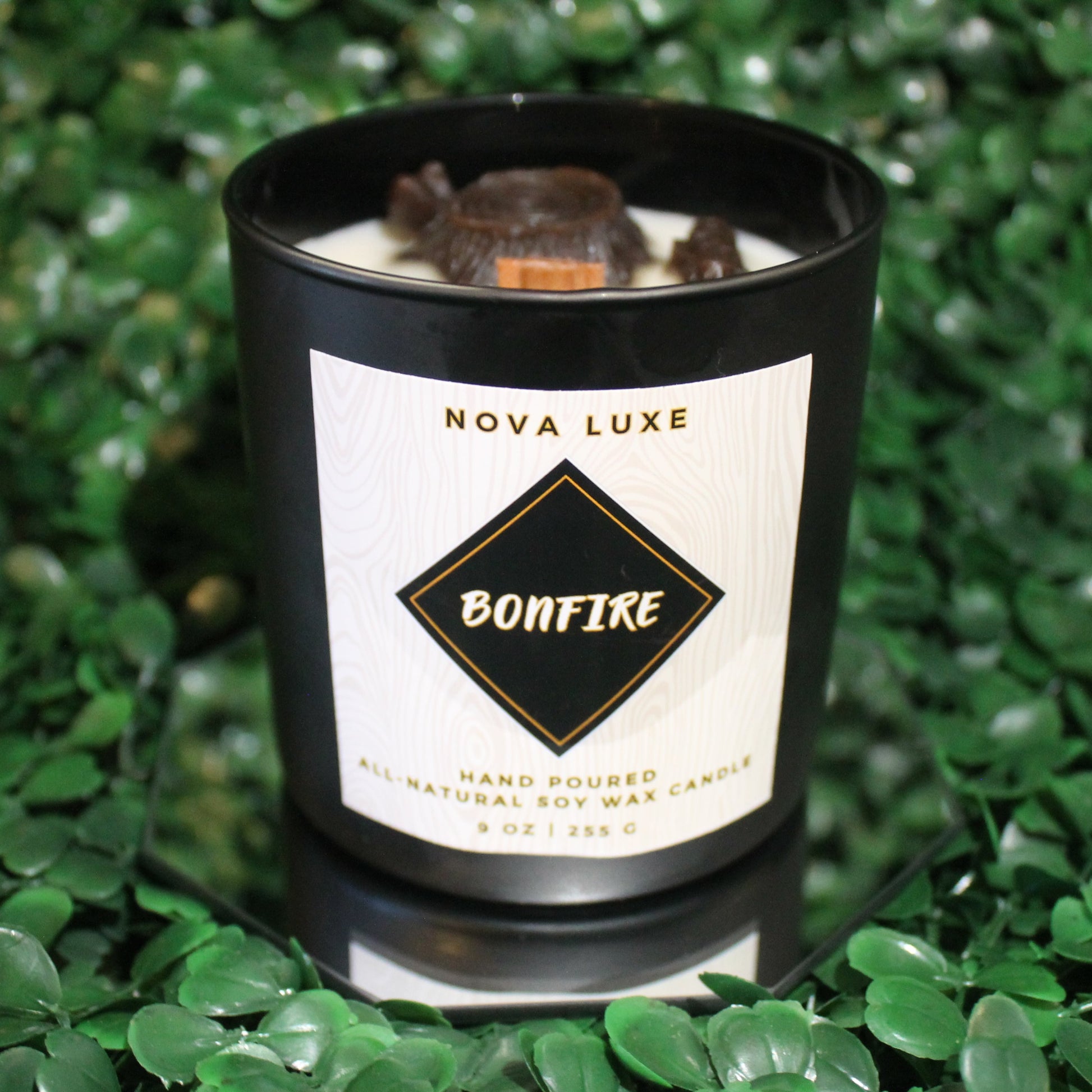 Nova Luxe Bonfire candle on a green leafy background